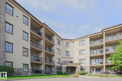 Multi-story residential building featuring a stucco exterior with stone accents - 117 160 Magrath Road, Edmonton, AB - Outdoor With Facade