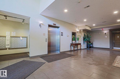 Lobby area featuring tile flooring, a stainless steel elevator, recessed lighting, and wall-mounted mailboxes - 117 160 Magrath Road, Edmonton, AB - Indoor Photo Showing Other Room