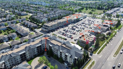 Aerial perspective showcasing the multi-story residential building and surrounding commercial properties - 117 160 Magrath Road, Edmonton, AB - Outdoor With View