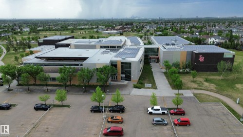Modern institutional building featuring a multi-level design with extensive solar panel installations on the roof - 117 160 Magrath Road, Edmonton, AB - Outdoor With View