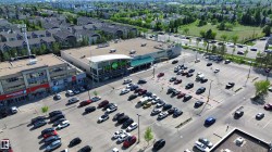 Commercial complex featuring a large surface parking lot, retail storefronts, and a grocery store - 