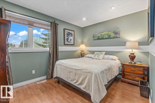 Wood-finish flooring throughout, featuring a large window with white trim, recessed lighting, and a chair rail molding - 6720 29 Avenue, Edmonton, AB 