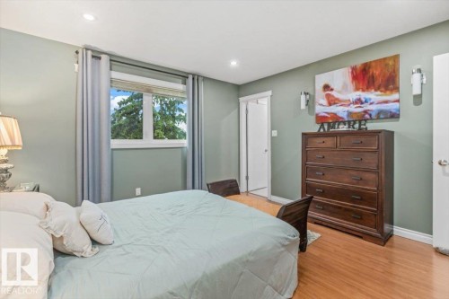 Spacious bedroom with wood-finish flooring, recessed lighting, and a large window - 6720 29 Avenue, Edmonton, AB 