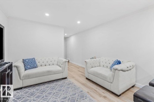 Open-concept living area featuring light wood-finish flooring, white walls, recessed lighting, and white baseboards - 6720 29 Avenue, Edmonton, AB 