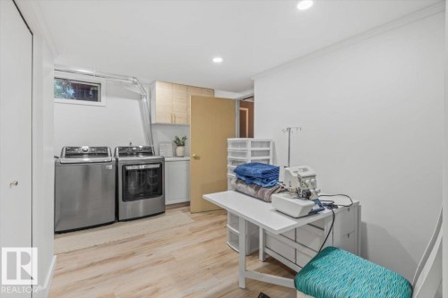 Dedicated laundry area featuring a window, built-in cabinetry, and wood-finish flooring - 6720 29 Avenue, Edmonton, AB 