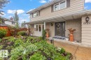 Exterior featuring tan siding, brick accents, a covered front entry with double doors, a bay window, and a terraced front garden - 6720 29 Avenue, Edmonton, AB 