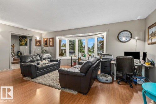 Living area featuring wood-finish flooring and a prominent bay window - 6720 29 Avenue, Edmonton, AB 