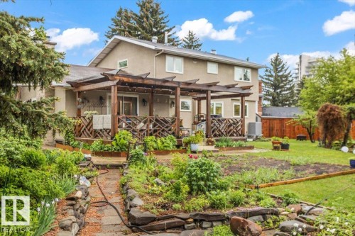 Rear exterior featuring a stucco facade, multiple windows, and a wood-slat pergola over a deck with decorative railing - 6720 29 Avenue, Edmonton, AB 