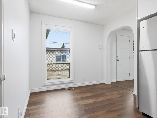Bright interior space featuring wood-finish flooring and a white trim window - 13316 136 Avenue, Edmonton, AB 