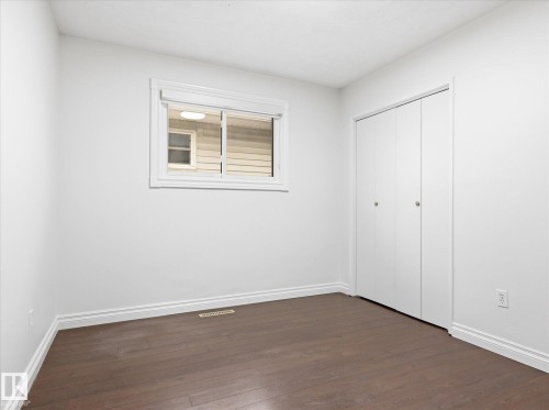 Neutral interior featuring dark wood-finish flooring, white baseboards, and white walls - 13316 136 Avenue, Edmonton, AB 