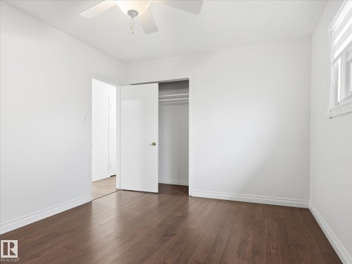 Bright room featuring wood-finish flooring, white walls, and a ceiling fan - 13316 136 Avenue, Edmonton, AB 