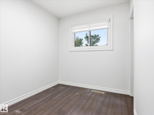 Bright room featuring wood-finish flooring, white walls, and white baseboards - 13316 136 Avenue, Edmonton, AB 