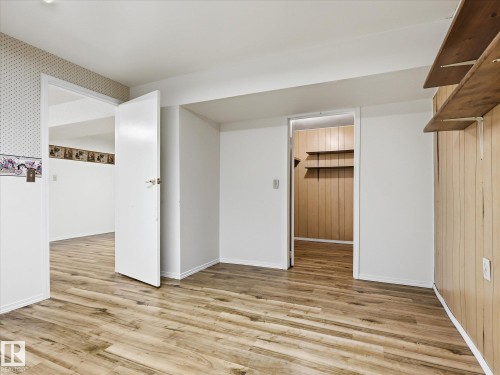 Spacious room featuring wood-finish flooring, white walls, and a white ceiling - 13316 136 Avenue, Edmonton, AB 