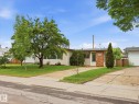 Ranch-style exterior with light-colored siding and a partial brick facade - 13316 136 Avenue, Edmonton, AB 