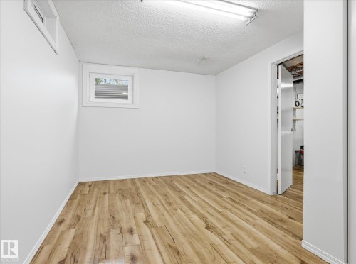 Room featuring wood-finish flooring, white painted walls, and a white trim baseboard - 13316 136 Avenue, Edmonton, AB 