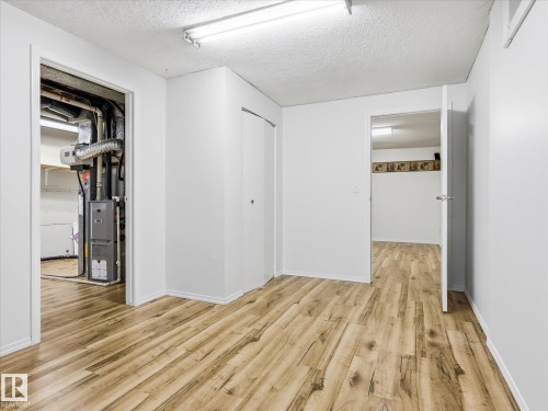 Open interior space featuring wood-finish flooring, white painted walls, and a textured ceiling - 13316 136 Avenue, Edmonton, AB 