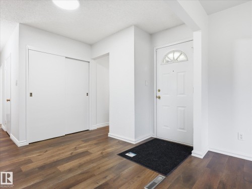 Entryway featuring a white paneled door with an arched transom window, wood-finish flooring, and a recessed ceiling light - 13316 136 Avenue, Edmonton, AB 