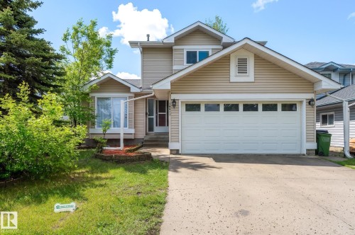 Front exterior featuring horizontal siding, an attached two-car garage with paneling and upper windows, a concrete driveway, and a front entry with a storm door - 16811 91 Street, Edmonton, AB 