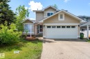 Front exterior featuring horizontal siding, an attached two-car garage with paneling and upper windows, a concrete driveway, and a front entry with a storm door - 16811 91 Street, Edmonton, AB 