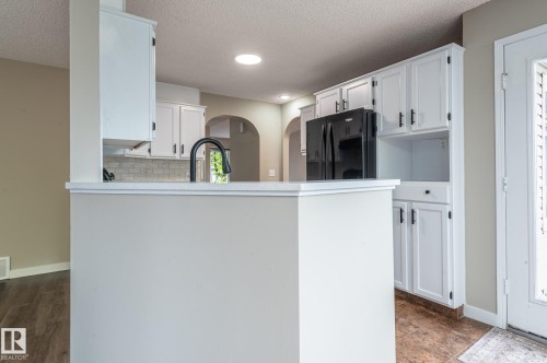 Kitchen featuring white cabinetry, a counter-height island with a black faucet, black appliances, and recessed lighting - 16811 91 Street, Edmonton, AB 