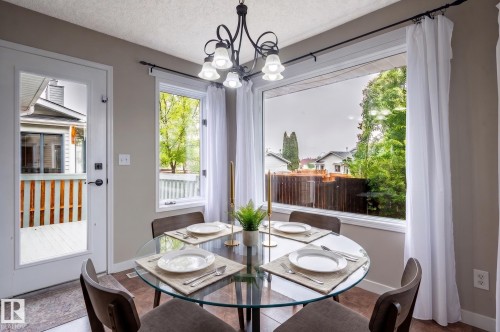 Dining area featuring a contemporary chandelier, large picture window, and wood-finish flooring - 16811 91 Street, Edmonton, AB 