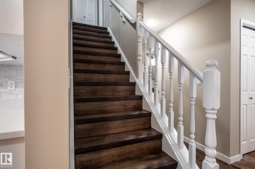 Staircase featuring wood-finish treads and risers, white balusters, and a white handrail - 16811 91 Street, Edmonton, AB 