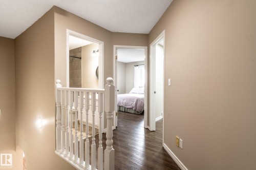 Hallway featuring wood-finish flooring, neutral wall tones, and white trim - 16811 91 Street, Edmonton, AB 