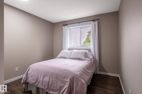 Bedroom featuring a window with white trim, wood-finish flooring, and light neutral wall paint - 16811 91 Street, Edmonton, AB 