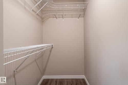 Walk-in closet featuring wire shelving, wire hanging rods, neutral wall paint, white baseboards, and wood-finish flooring - 16811 91 Street, Edmonton, AB 