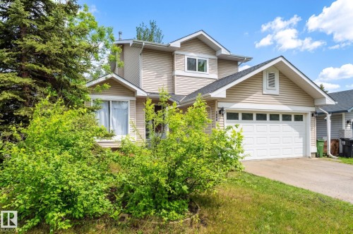 Two-story residential exterior featuring light-colored horizontal siding, a prominent two-car garage with panel detailing, and a dark shingle roof - 16811 91 Street, Edmonton, AB 