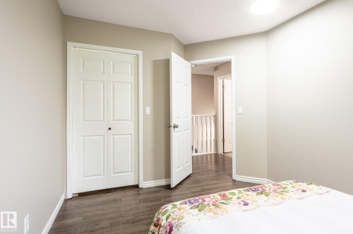 Bedroom featuring wood-finish flooring, light grey painted walls, white baseboards, and a white ceiling with a flush-mount light fixture - 16811 91 Street, Edmonton, AB 