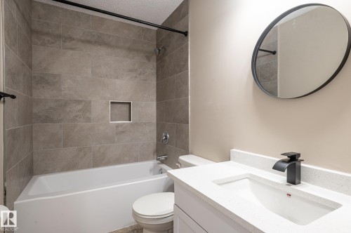 Bathroom featuring a shower-tub combination with large format tile surround and an integrated niche - 16811 91 Street, Edmonton, AB 