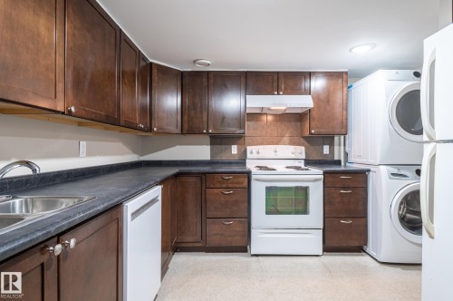 Efficient kitchen space featuring dark wood-finish cabinetry and contrasting dark countertops - 16811 91 Street, Edmonton, AB 