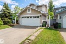 Front exterior featuring light-colored siding, a white garage door with windows, and a concrete driveway - 16811 91 Street, Edmonton, AB 
