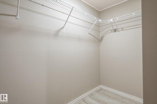 Interior closet featuring wire shelving, light neutral wall paint, white baseboards, and wood-finish flooring - 16811 91 Street, Edmonton, AB 