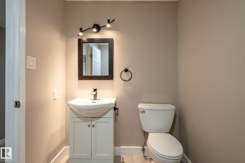 Powder room featuring a white pedestal vanity, a dark framed mirror, and a track light fixture with three spotlights - 16811 91 Street, Edmonton, AB 