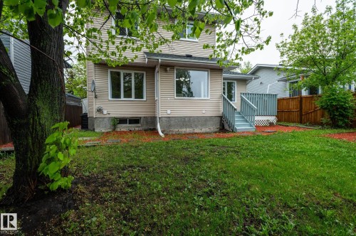 Spacious backyard featuring a grass lawn, mature tree, and a wooden deck with railing - 16811 91 Street, Edmonton, AB 