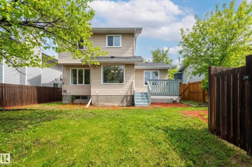 Rear exterior with beige siding, multiple windows, and a wood deck with lattice skirting - 16811 91 Street, Edmonton, AB 