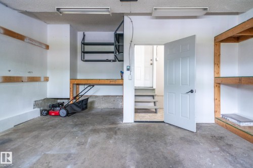 Spacious garage featuring concrete flooring and fluorescent overhead lighting - 16811 91 Street, Edmonton, AB 