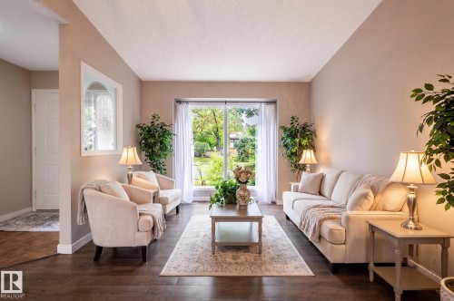 Bright living area featuring wood-finish flooring, neutral-toned walls, and a large sliding glass door - 16811 91 Street, Edmonton, AB 