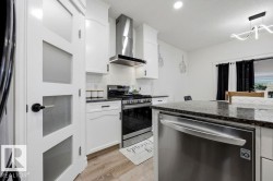 Modern kitchen featuring white cabinetry, subway tile backsplash, stainless steel appliances, granite countertops, and wood-finish flooring - 