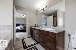 Double vanity with integrated sinks and dark wood-finish cabinetry, set against light-toned walls - 