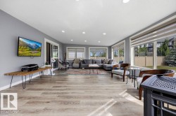 Open-concept living area featuring light wood-finish flooring, a wall of windows with horizontal blinds, recessed ceiling lighting, a sliding glass door, and neutral gray wall paint - 