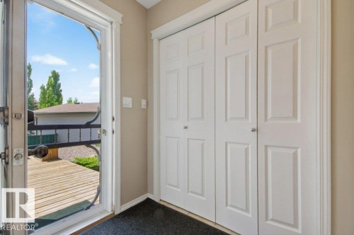 Entryway with bifold closet doors and a glass-paneled storm door opening to an outdoor deck - 12215 18 Avenue Sw, Edmonton, AB 