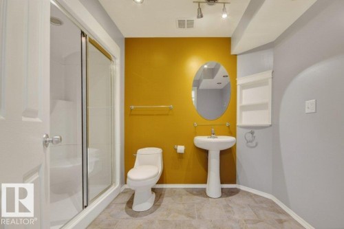 Pedestal sink with an oval mirror, track lighting, and a glass-enclosed shower - 12215 18 Avenue Sw, Edmonton, AB 