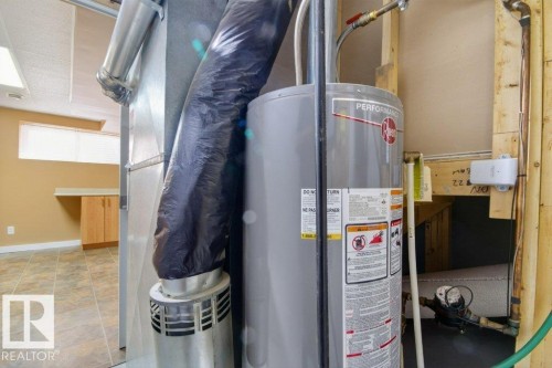 Utility area featuring a water heater, furnace system, and exposed framing - 12215 18 Avenue Sw, Edmonton, AB 