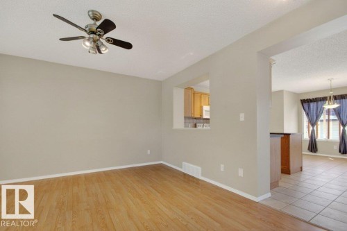 Interior room featuring light wood-finish flooring, a ceiling fan with integrated lighting, and neutral wall paint - 12215 18 Avenue Sw, Edmonton, AB 