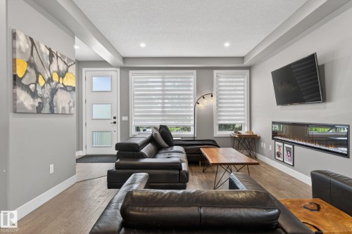 Open concept living area featuring wood-finish flooring, recessed lighting, and a modern linear electric fireplace - 8809 148 Street, Edmonton, AB - Indoor Photo Showing Living Room With Fireplace