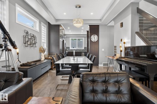 Open-concept living area with wood-finish flooring, a contemporary chandelier, and recessed lighting - 8809 148 Street, Edmonton, AB - Indoor Photo Showing Living Room