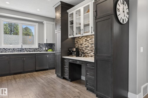 Kitchen featuring wood-finish flooring, two-tone cabinetry, mosaic tile backsplash, recessed lighting, and a built-in workstation - 8809 148 Street, Edmonton, AB - Indoor